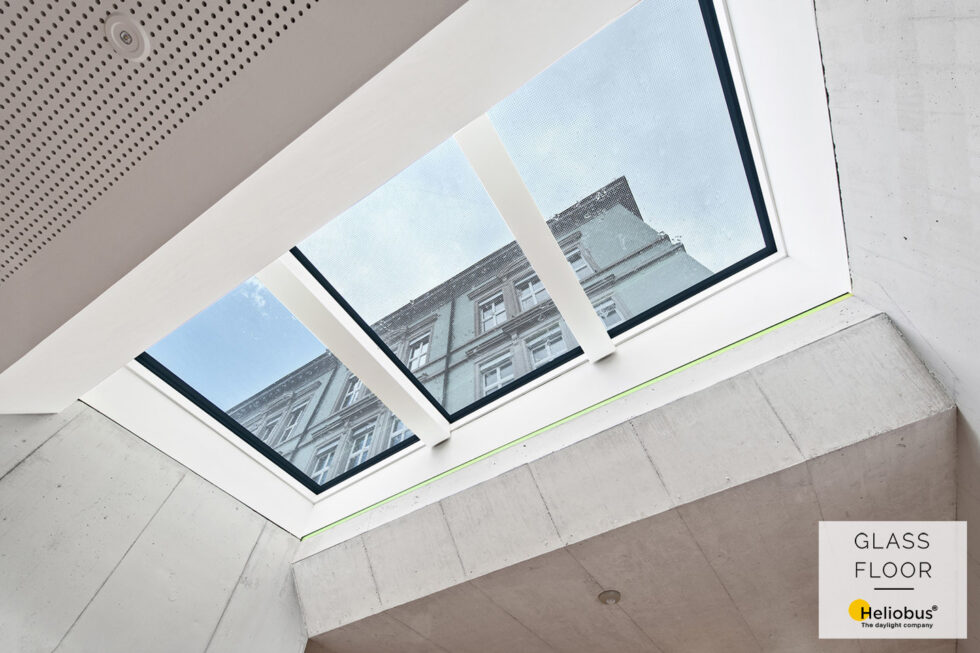 Výhled na okolní dům přes pojezdový světlík Glassfloor osazený do suteréních prostor pro osvětlení denním světlem